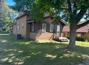 A two-story house with a front porch, a small deck, and a well-maintained lawn.