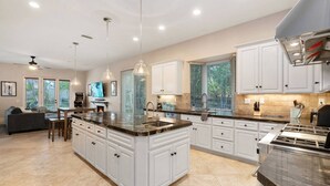 A spacious kitchen with white cabinetry, a granite countertop, and a central island. - The Huntington Spacious Family Friendly (Poway)