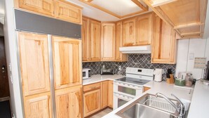 A kitchen with wooden cabinets, a stainless steel sink, a microwave, a toaster, and a stove. - 10 Steps to the Slopes! Unbeatable Ski-In/Ski-Out! Hot Tub! (Mount Crested Butte)