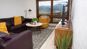 A modern living room with a leather sofa, a coffee table, a yellow armchair, and a TV on a wooden stand. - 10 Steps to the Slopes! Unbeatable Ski-In/Ski-Out! Hot Tub! (Mount Crested Butte)