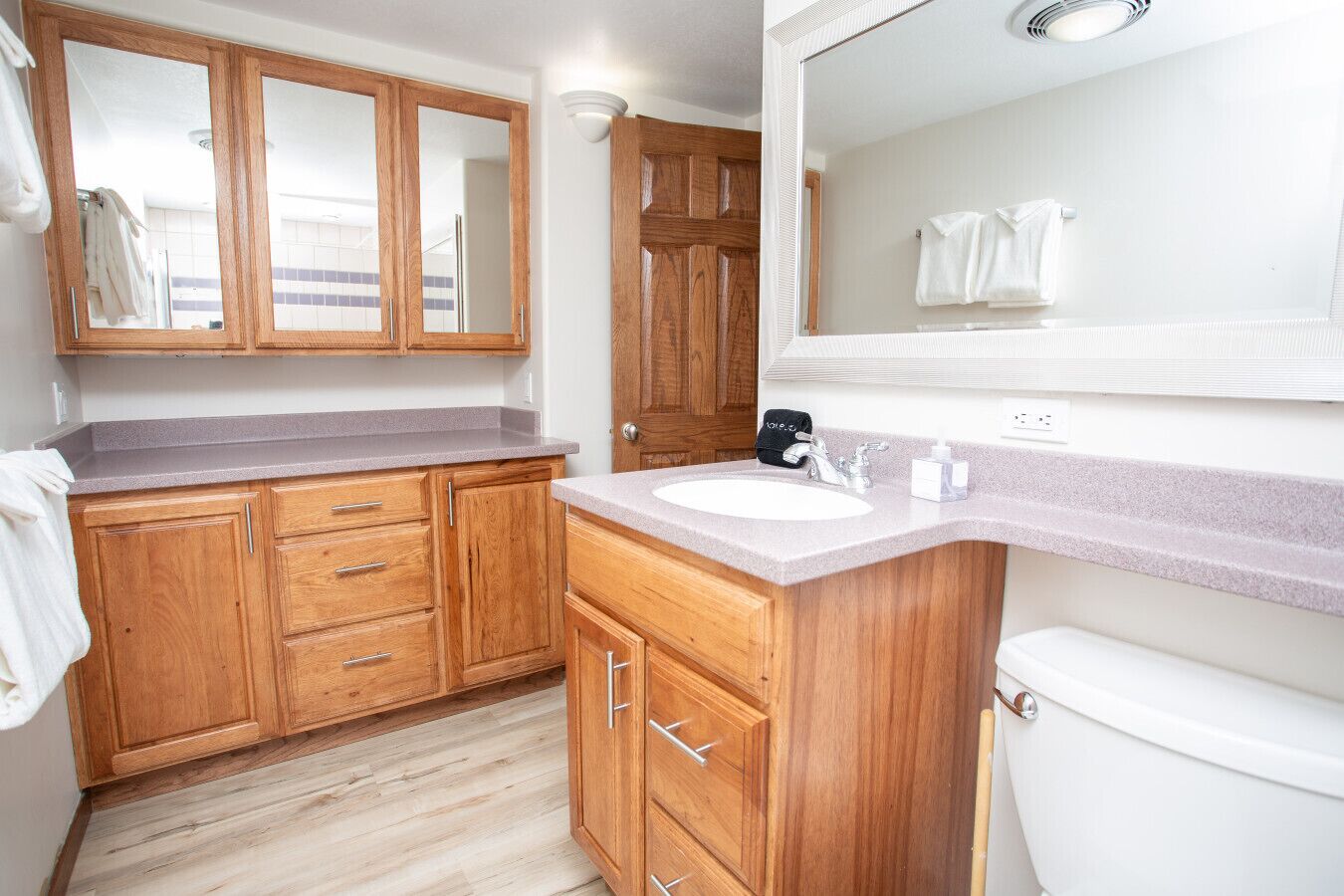 Une salle de bain moderne avec des meubles en bois, un lavabo blanc et un grand miroir.