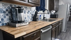 A kitchen with a wooden countertop, a coffee maker, a sink, and a dishwasher. - NEW GAME ROOM Quiet, Comfortable, Spacious Home Near OSU! (Stillwater)
