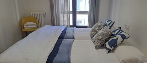 Une chambre d’hôtel avec un lit, une chaise et une fenêtre avec des rideaux.