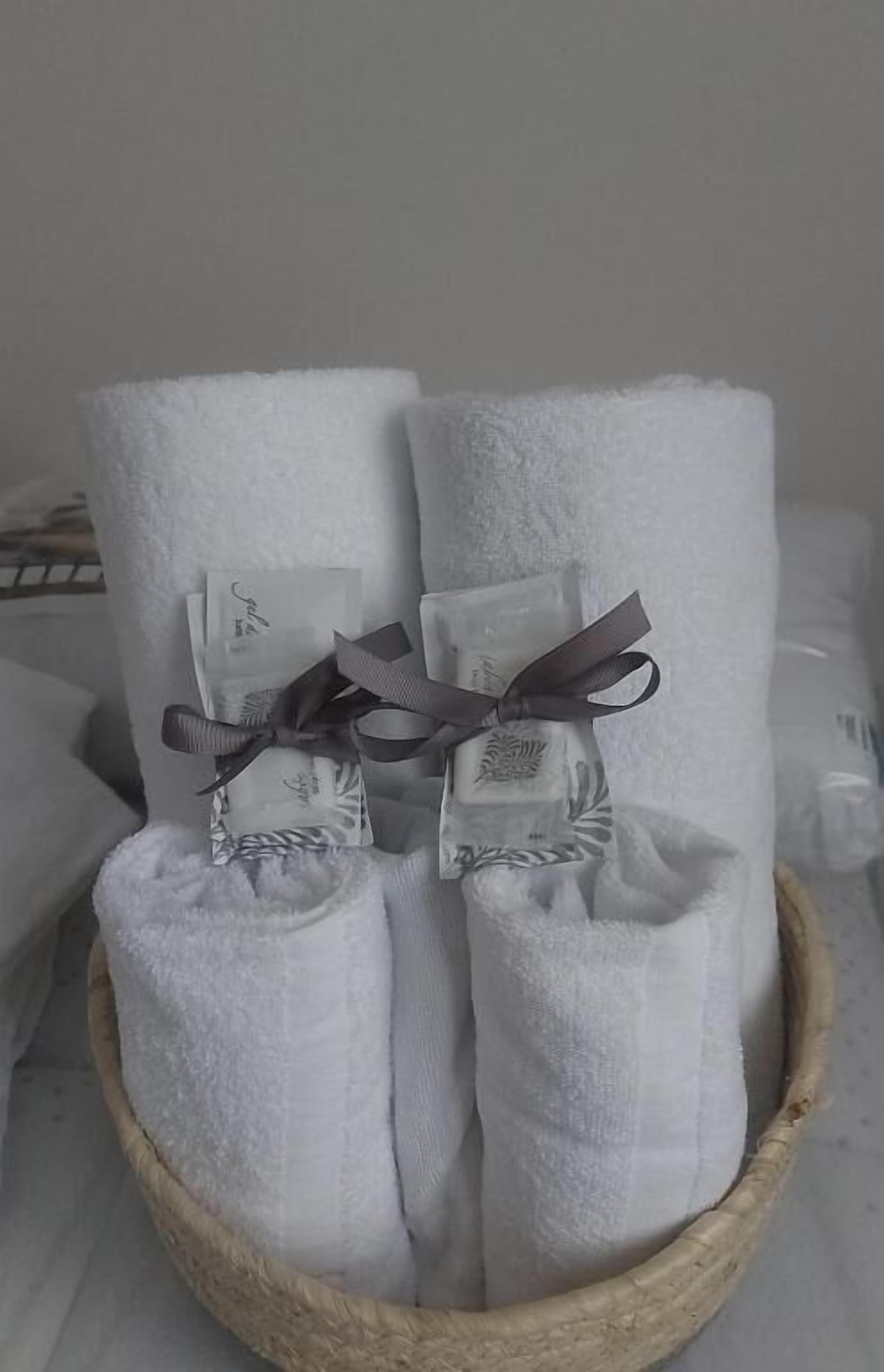 Una cesta con toallas blancas dobladas y pequeñas bolsas de regalo atadas con cintas.