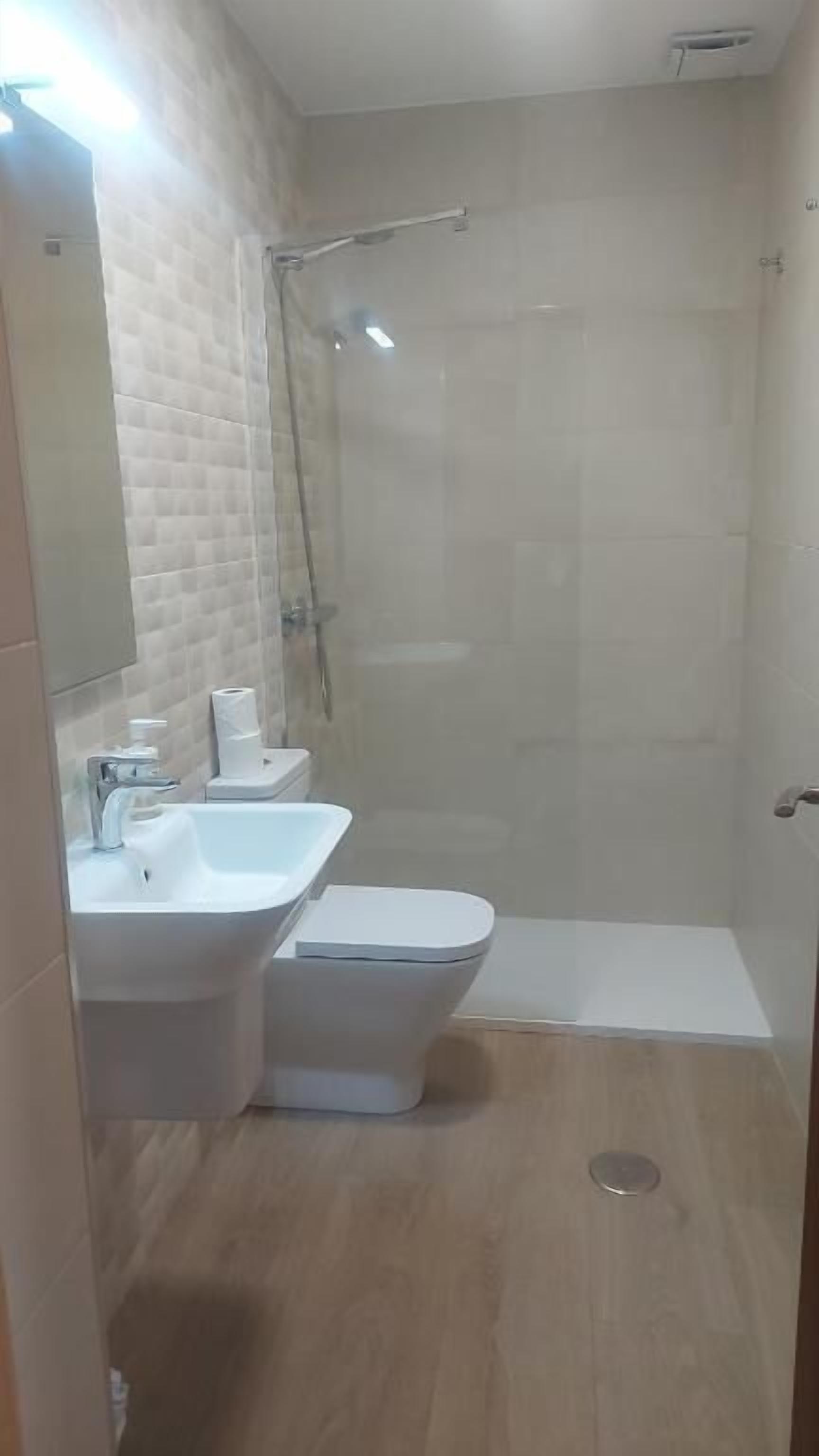 Ein Badezimmer mit Dusche, Toilette und Waschbecken.