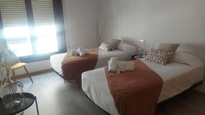 Une chambre d’hôtel avec deux lits, chacun recouvert d’une couverture marron et agrémenté de serviettes blanches. On y trouve une table de chevet avec une lampe, ainsi qu’une chaise équipée d’un ventilateur.