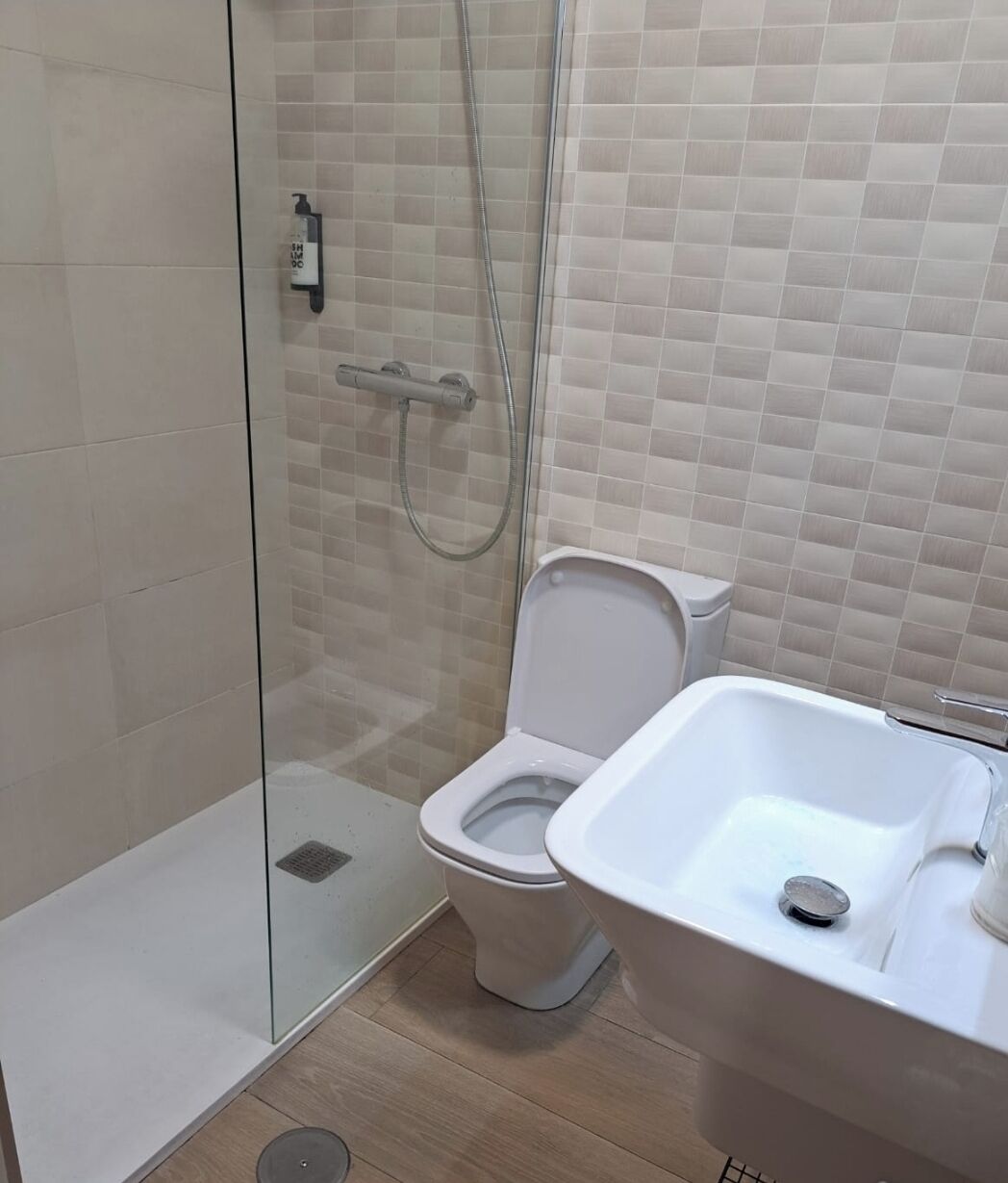 Une salle de bain avec une douche à parois de verre, des toilettes et un lavabo.