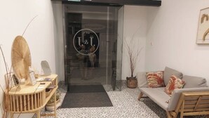 Un espace d’accueil doté d’un sol à motifs, d’un canapé, d’une table en bois et d’une porte en verre ornée d’un logo.