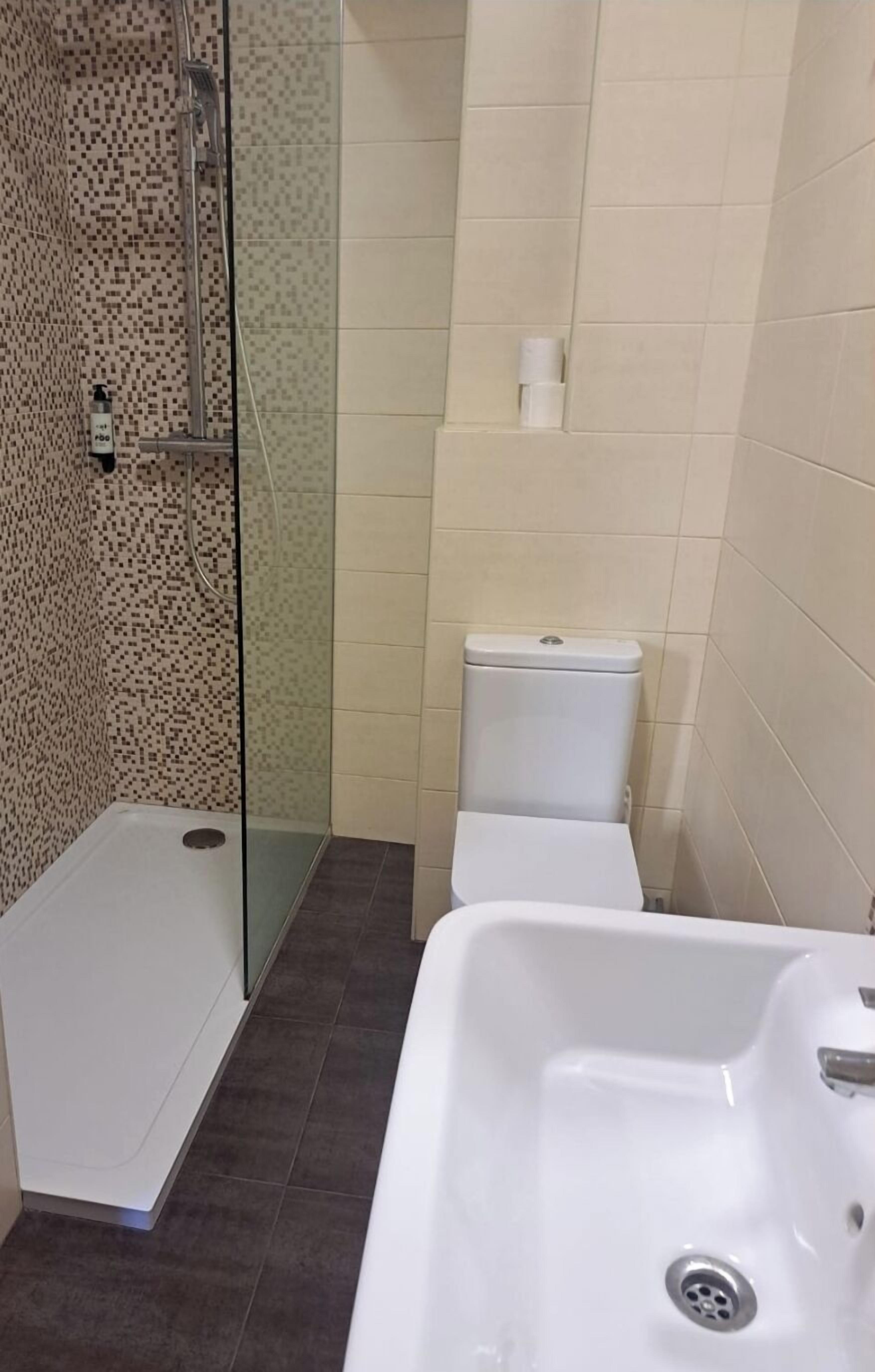 A bathroom with a shower, toilet, and sink.