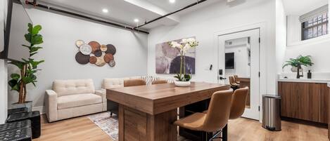 Una cocina moderna con una isla de madera, taburetes de bar, encimera blanca y un bote de basura de acero inoxidable.