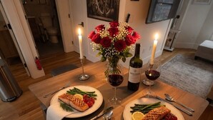 Una mesa de comedor con dos platos de comida, velas y una botella de vino.