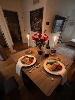 Una mesa de comedor con dos platos de comida, velas y una botella de vino.