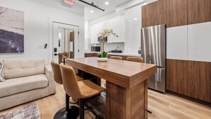 Una cocina moderna con una isla central, armarios de madera y un refrigerador de acero inoxidable.