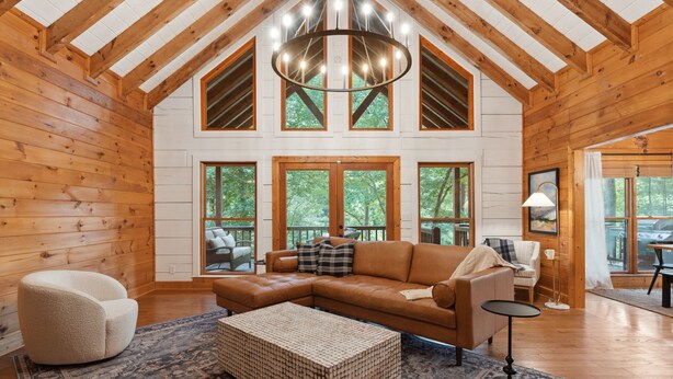 A spacious living room with a large sectional sofa, a round coffee table, and a chandelier. - The Hidden Still~Blue Ridge Speakeasy Lakehouse~SLEEPS 22 (Cherry Log)