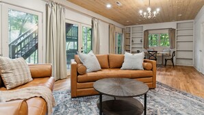 A spacious living room with a leather sofa, a coffee table, and a bookshelf. - The Hidden Still~Blue Ridge Speakeasy Lakehouse~SLEEPS 22 (Cherry Log)