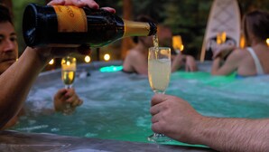 A person pouring champagne into a glass at a hot tub. - The Hidden Still~Blue Ridge Speakeasy Lakehouse~SLEEPS 22 (Cherry Log)