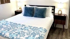 Een hotelkamer met een groot bed, twee nachtkastjes, een wandklok en twee ronde decoratieve objecten aan de muur.