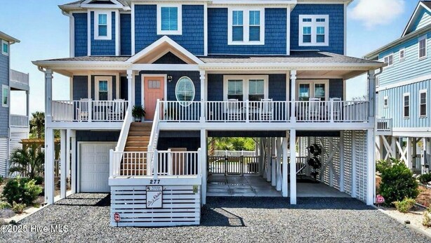 A two-story house with a balcony, a garage, and a covered entryway. - Luxurious, Newly Furnished Home w/ stunning views & just steps from the beach (Ocean Isle Beach)