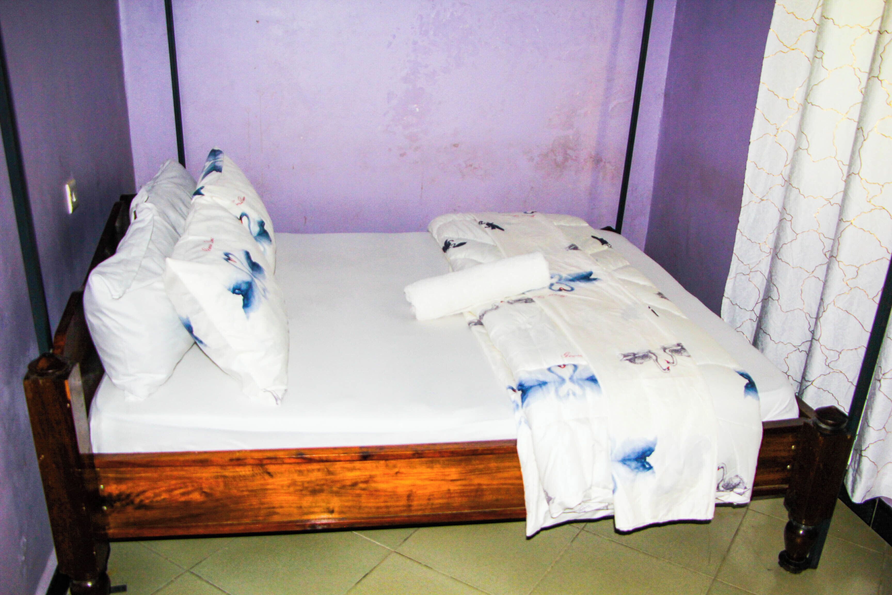 A single bed with a wooden frame, white bedding, and a floral pattern.
