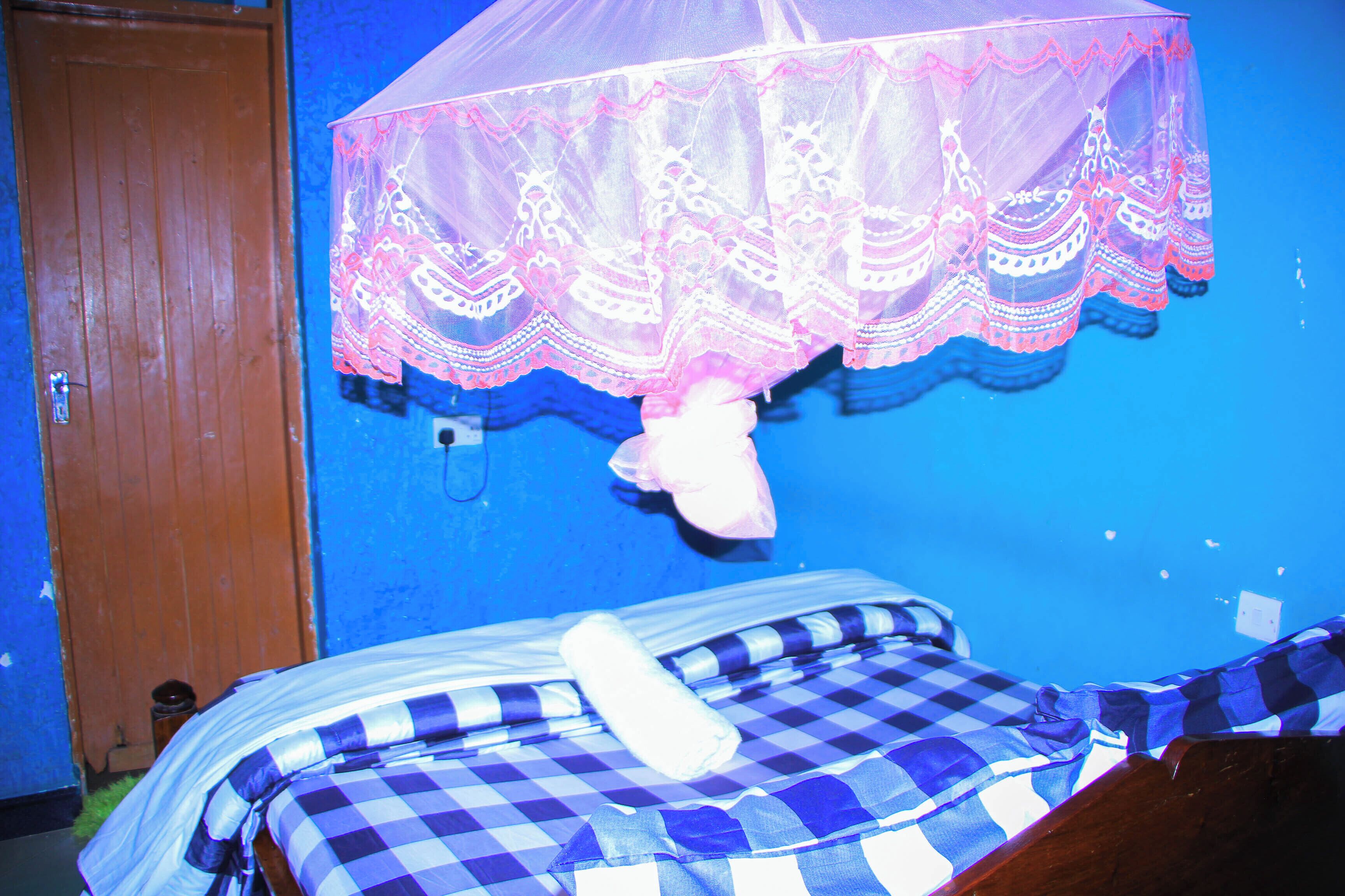 A room with a bed covered in checkered bedding, a wooden door, and a blue wall.