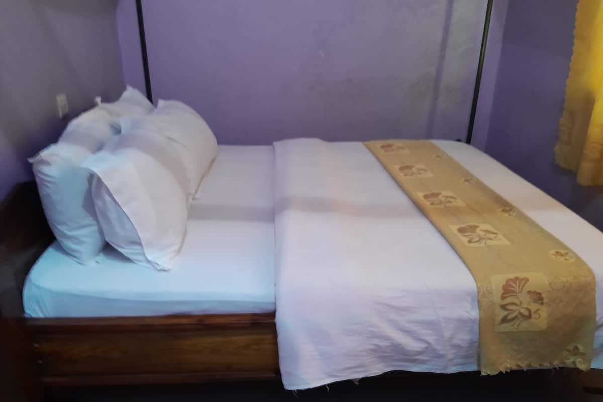 Uma cama de solteiro com roupa de cama branca e cabeceira decorativa.