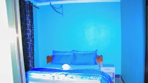 A small, single-bed room with a wooden headboard, a bedside table, and a nightstand. - HAPPY CLASSIC LODGE MBEYA (Mbeya)