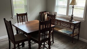 A dining room with a wooden table and chairs, a bench, and a lamp.
