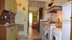 A compact kitchen with a washing machine, a sink, and a small countertop. There is a door leading to another room. - Cicci's house (Cefalù)