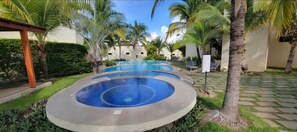 A circular pool with a blue center, surrounded by palm trees and a paved walkway. - Gorgeous Ocean View Rooftop Patio, Private gated 2 bedroom home, Walk to beach (Coco)