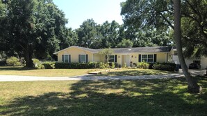 A single-story house with a front yard, a driveway, and a street view. - Tampa Lakehouse 6-bedroom houses on a acre (Tampa)