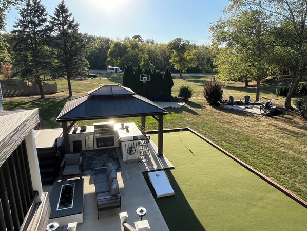 A backyard with a covered barbecue area, outdoor seating, and a well-maintained lawn. - Plenty of room for all! Three floors of comfort and an entertaining backyard (Bettendorf)