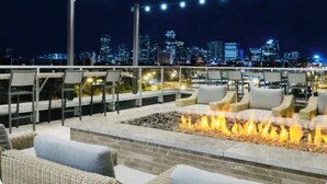 An outdoor seating area with a fire feature and city skyline views. - Elite Resort Home • Pool, Jacuzzi, Basketball • Sleeps 16+ King Beds•Shuttle (Everett)