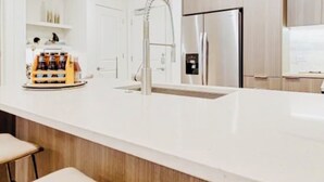 A modern kitchen with a white countertop, stainless steel appliances, and wooden cabinets. - Elite Resort Home • Pool, Jacuzzi, Basketball • Sleeps 16+ King Beds•Shuttle (Everett)
