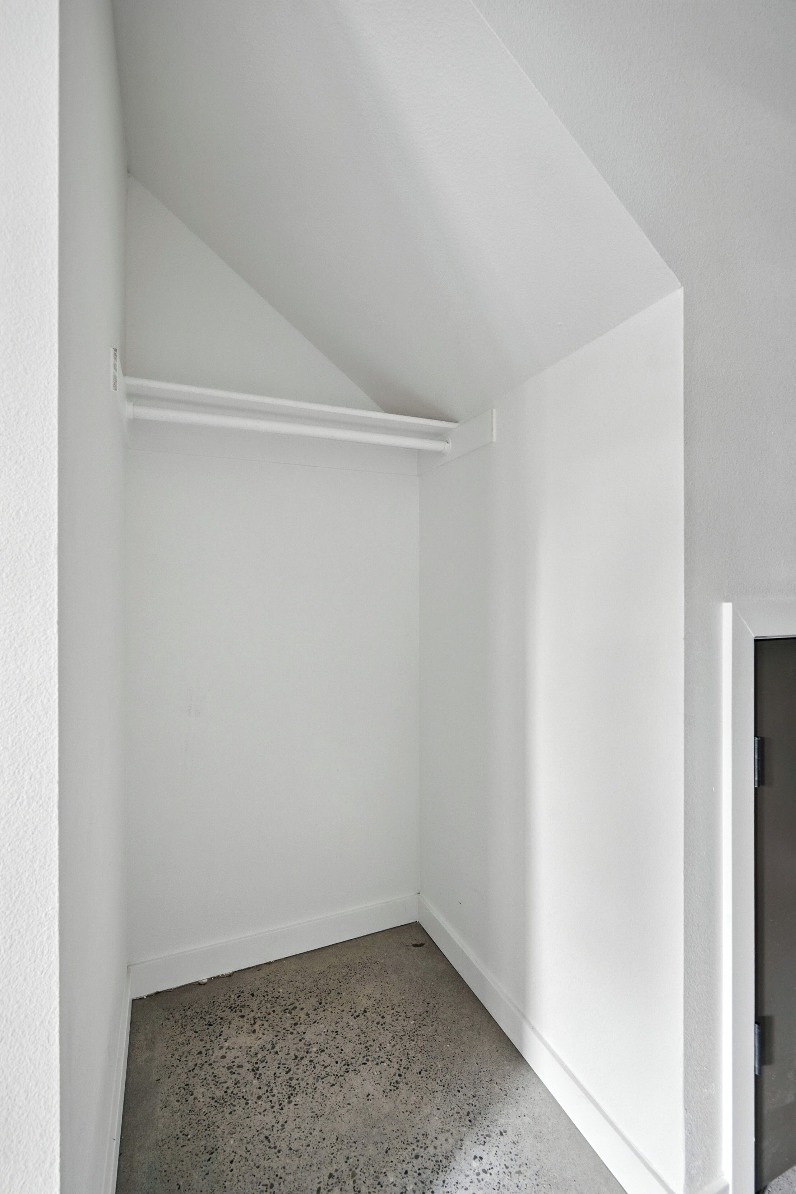 A corner room with white walls, a concrete floor, and a white ceiling.