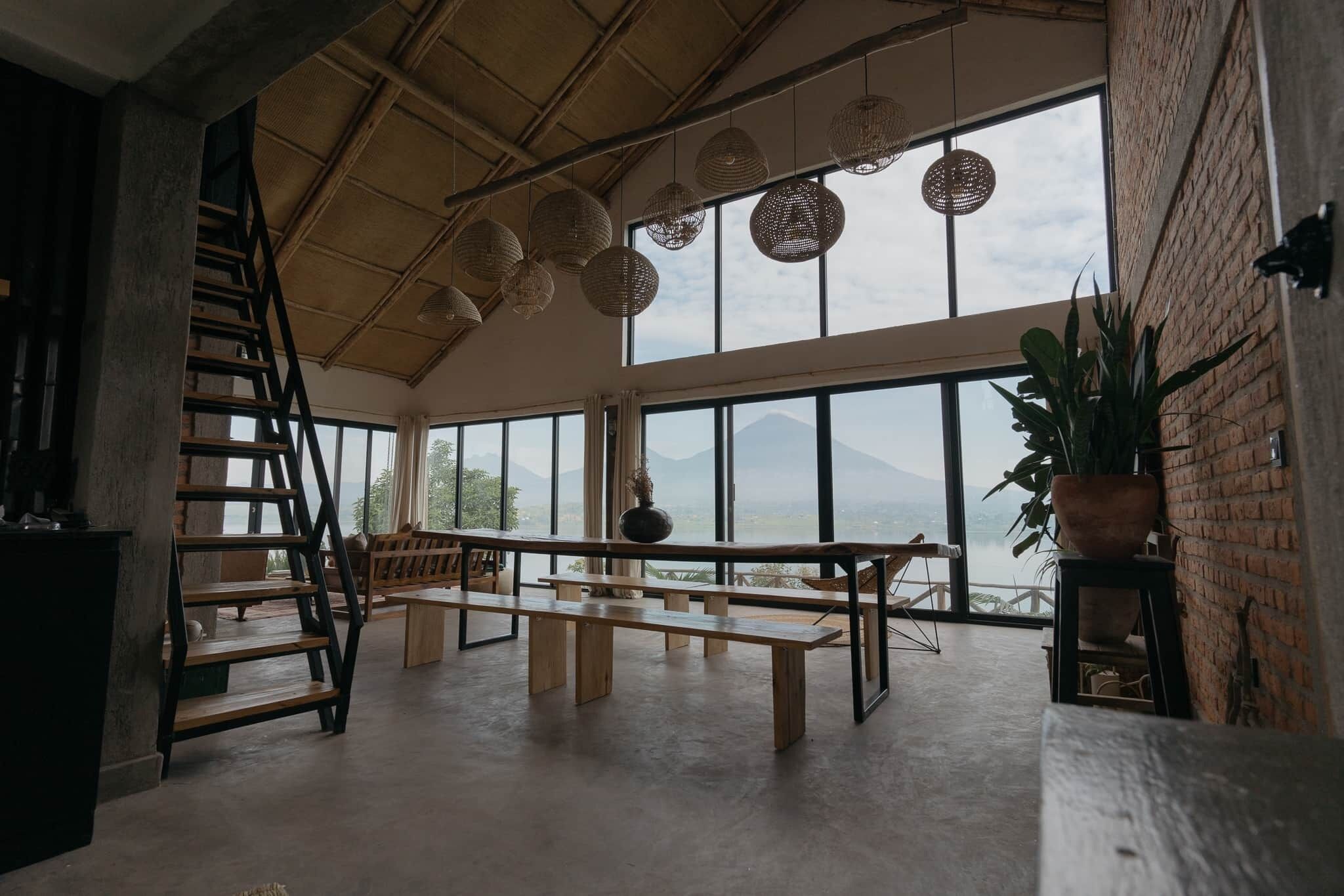 A spacious room with a large window offering a mountain view, a wooden bench, and a staircase.