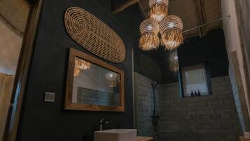 A bathroom with a wooden vanity, a large mirror, and a woven light fixture.