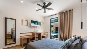 Ein Schlafzimmer mit Bett, Schreibtisch, Stuhl und Deckenventilator.