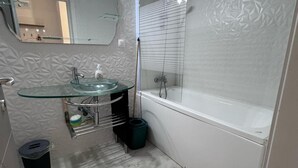 Un bagno con lavabo in vetro, uno specchio, una doccia e una vasca da bagno.