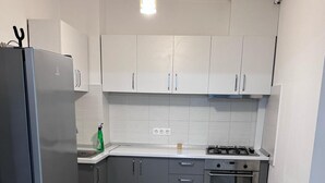 Una cucina moderna con mobili bianchi, frigorifero in acciaio inossidabile, piano cottura a gas e forno integrato.