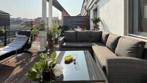 A rooftop terrace with a sofa, lounge chairs, and potted plants. - Casa Laura in Milano (Milan)