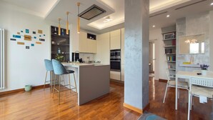 A modern kitchen with a central island, bar stools, and a built-in oven. - Casa Laura in Milano (Milan)