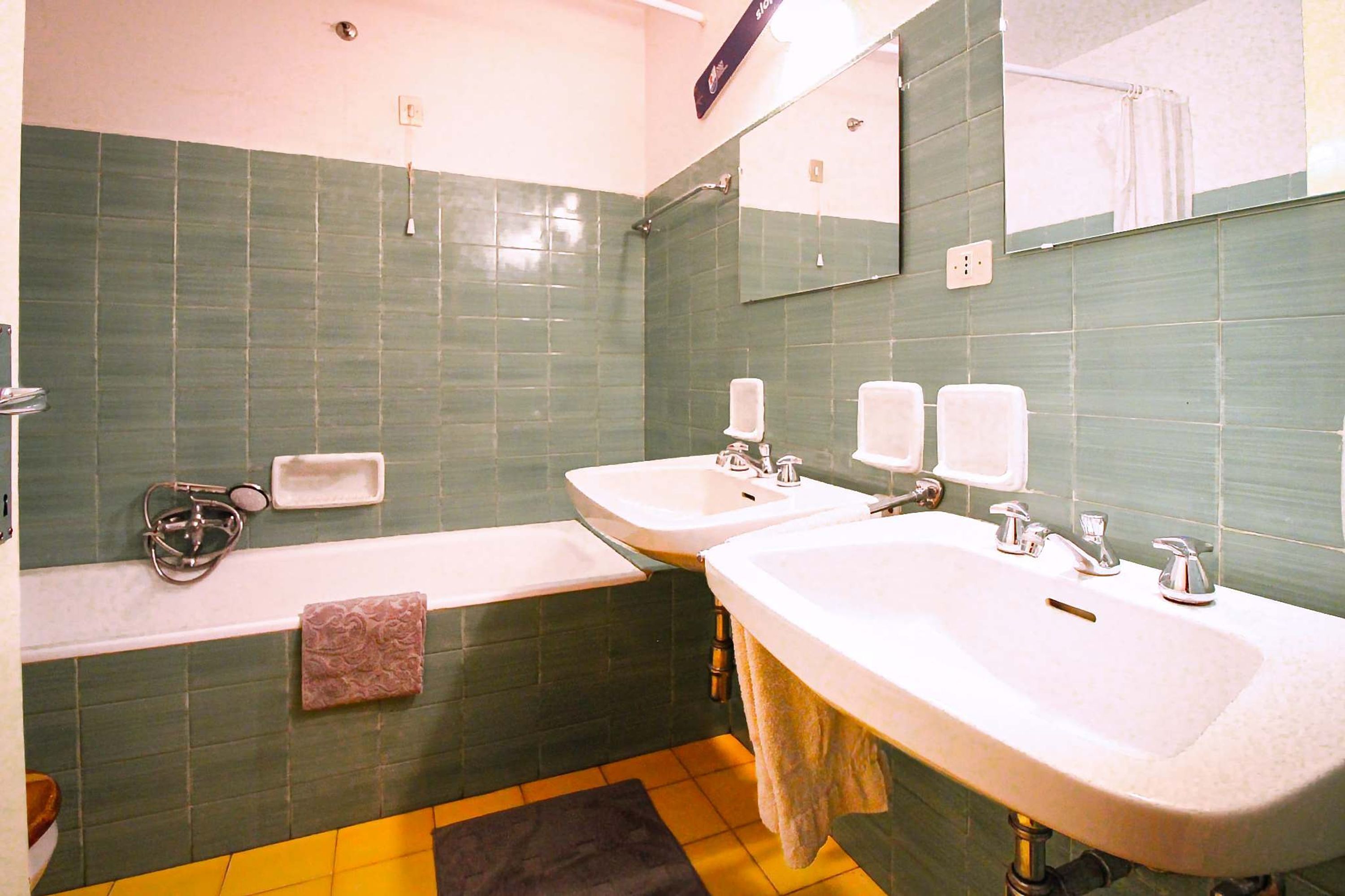 Une salle de bain avec deux lavabos, une baignoire et un miroir.