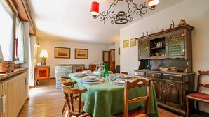 A dining room with a green tablecloth, wooden chairs, and a cabinet with glassware. - Ca Del Molin in Cortina d Ampezzo (Cortina d'Ampezzo)