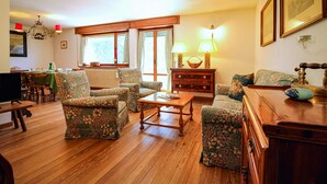A cozy living room with floral-patterned furniture, a wooden coffee table, and a fireplace. - Ca Del Molin in Cortina d Ampezzo (Cortina d'Ampezzo)