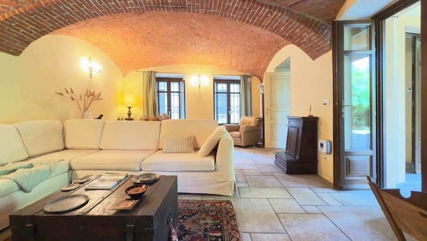 A spacious living room with a brick ceiling, a large sofa, a coffee table, and a rug.