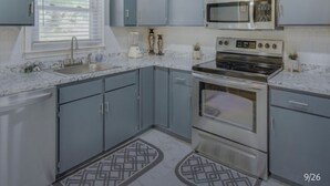 Una cocina compacta con armarios grises, un microondas integrado, una estufa y un lavabo.