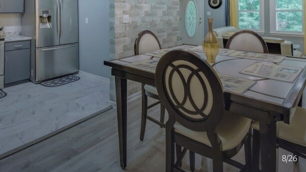 Una cocina moderna con un refrigerador de acero inoxidable, una mesa de comedor con sillas y una araña.