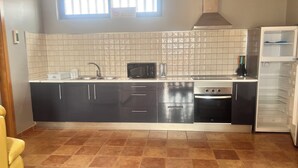 A kitchen with a microwave, oven, and refrigerator. There is a window above the sink and a tiled backsplash. - La Cuadra, where time stands still. (El Time)