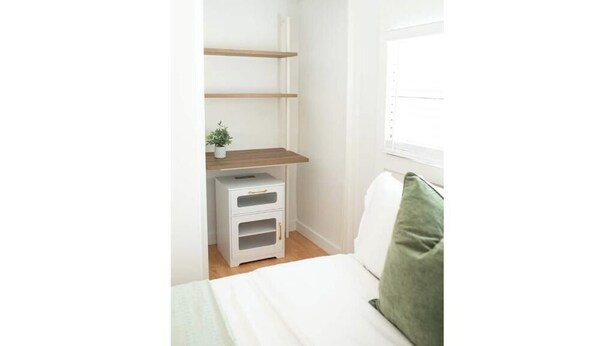 A bedroom with a bed, a nightstand, a dresser, and a window. - -The Villa On The Lake- (Groveland)