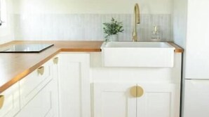 A kitchen with white cabinets, a wooden countertop, a sink, and a refrigerator. - -The Villa On The Lake- (Groveland)